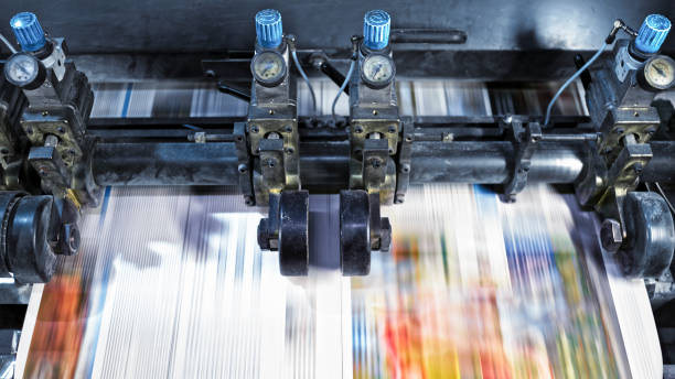 Blurred motion of newspaper sheet being cut into pages by the machine in the printing factory.
